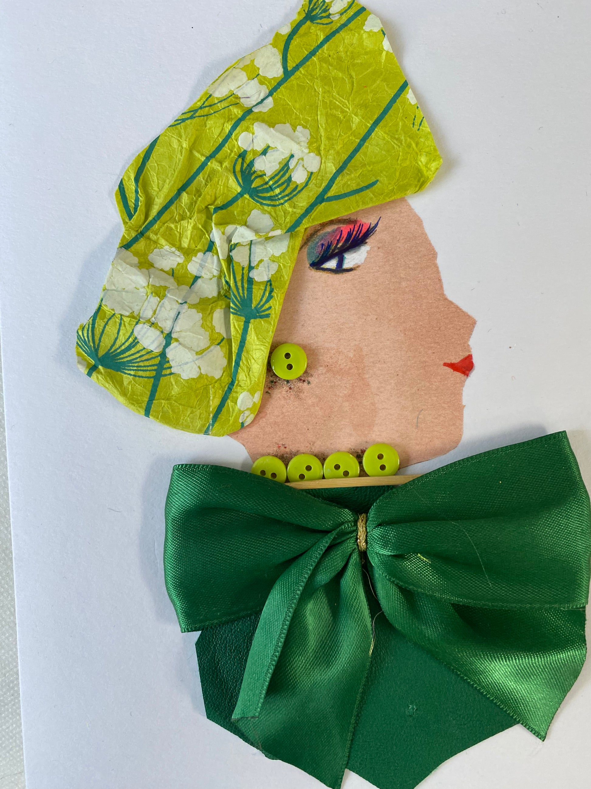 I designed this card of a woman named Goldie Glorious. She has a white skin tone and is wearing light green headwrap with white flowers on it. She wears a silk emerald green blouse with a silk green bow. She wears pretty light green button jewellery. 