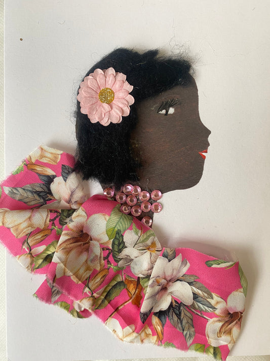 I designed card of a woman named Bella Bakerloo. She has a black skin tone and wears a pink flower in her hair. She wears a pink floral blouse. She wears pink gem jewellery.