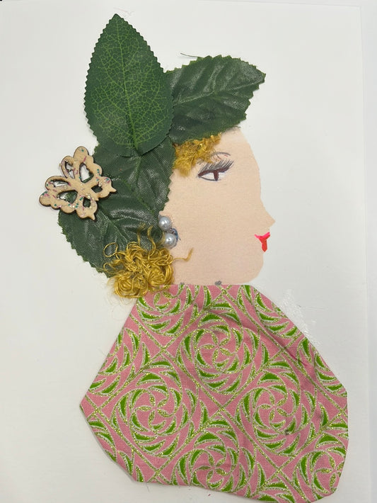 This card is called Gosia. She wears a pink and green patterned blouse, and has green leaves in her blonde hair as well as a small butterfly.
