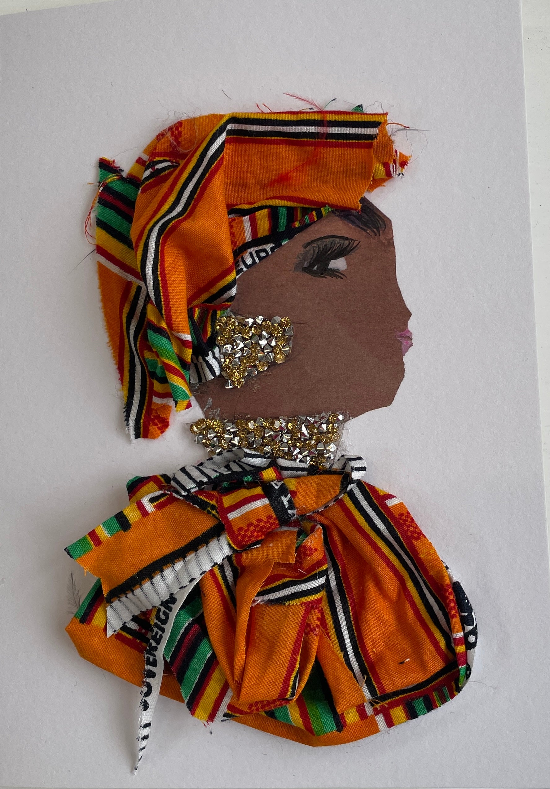 This card is called Goldie. She wears an orange patterned headdress and blouse, and gold diamanté jewellery.  