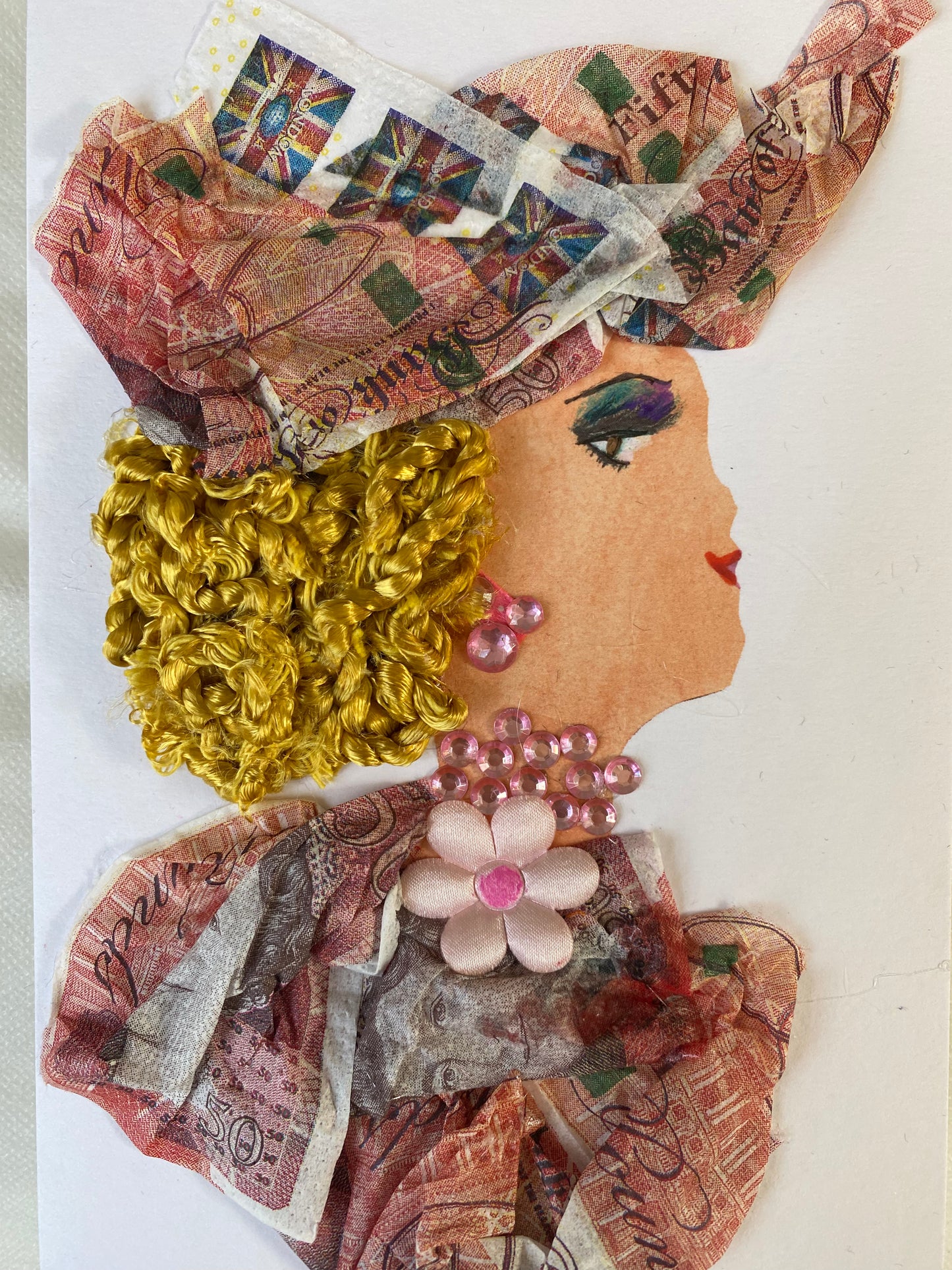 I designed this card of a woman called Donut Peach Moni. She has a white skin tone with curly yellow hair. She wears a money print hat with a matching money print blouse. On her blouse there is a pink flower in the middle. She wears pink gem jewellery.