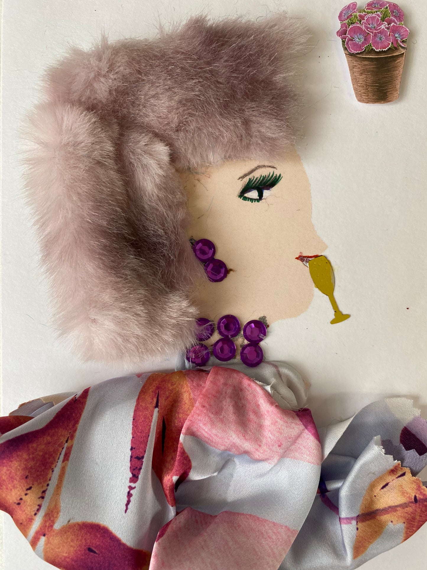  I designed this card of a woman who is wearing a pink furry hat. She is wearing a pink floral blouse. She is wearing purple gem jewellery. By her mouth there is a glass. In the corner there is a bouquet of pink flowers.