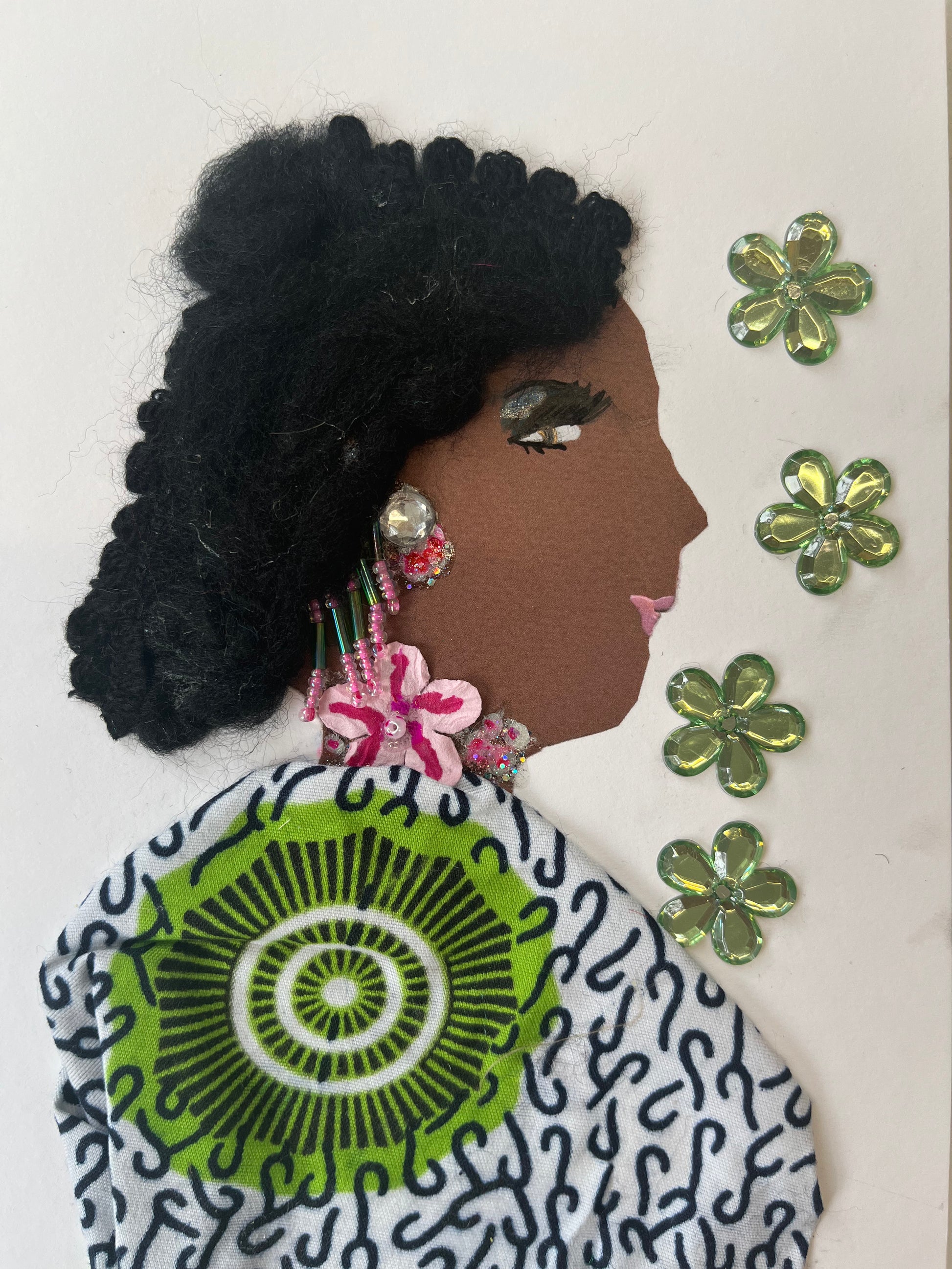 This card is of a woman given the name Amy. Amy wears a black, white, and green patterned blouse, a necklace with a pink flower on it, and she has medium length black hair. To her right, there are four green flower crystals. 