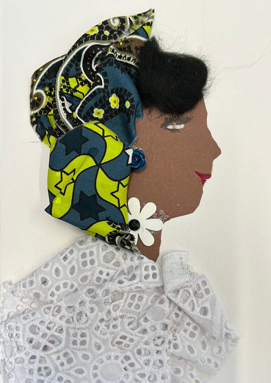 This card was given the name Tola. Tola wears a white blouse made of an eyelet material, a headscarf with various greens in it, and a white flower around her neck with a black center.