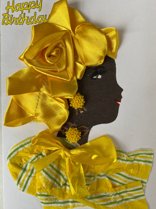 This card features a woman adorned in an opulent yellow silk head wrap and a striking striped blouse accessorized with a canary yellow ribbon. A delightful flowery jewelry complements her look, while the top corner displays the words 'Happy Birthday' in a brilliant golden hue.