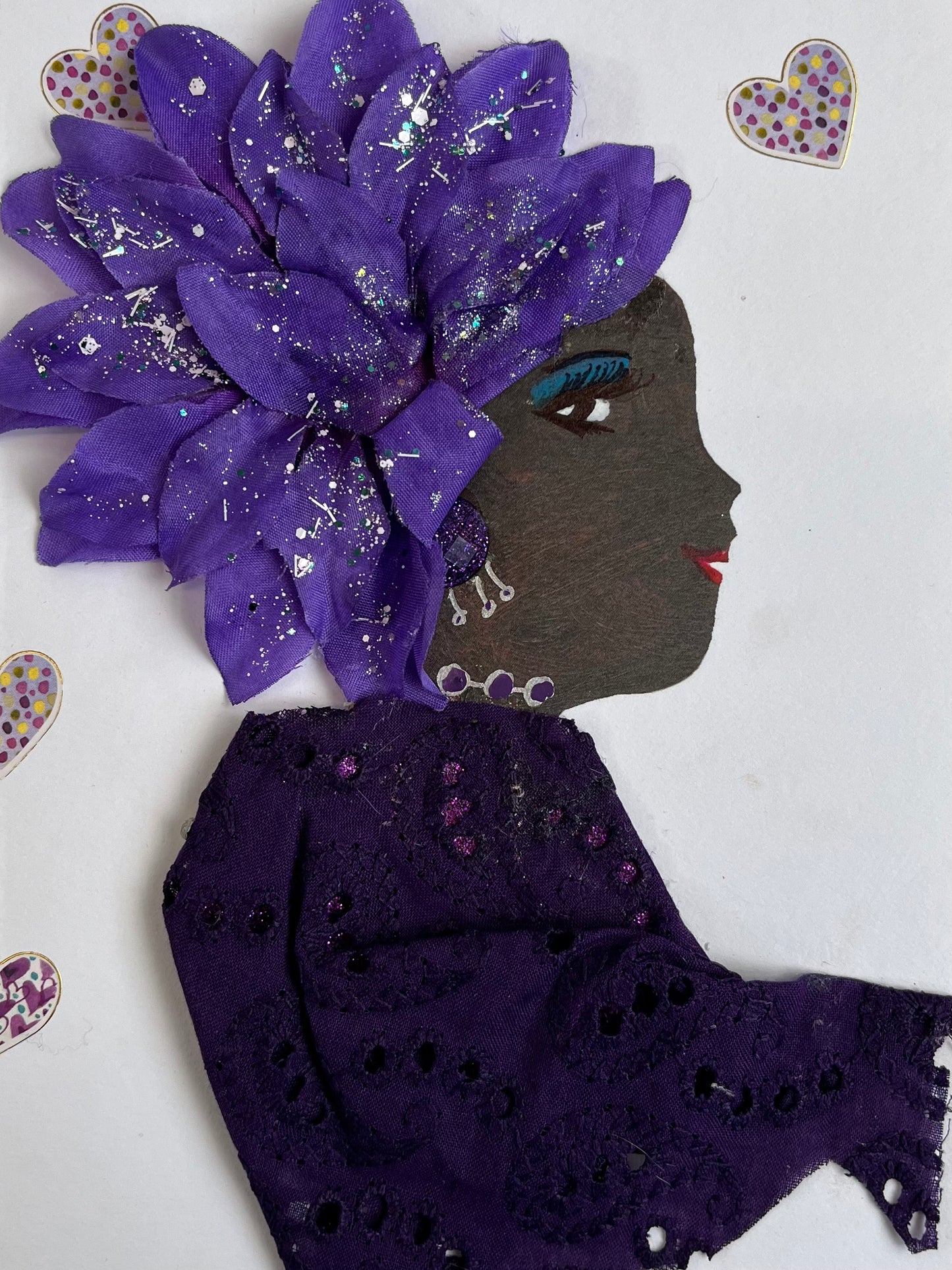 This card is called Jamie. She wears a purple eyelet blouse and a large purple flower in her hair. Surrounding her there is small purple hearts. 
