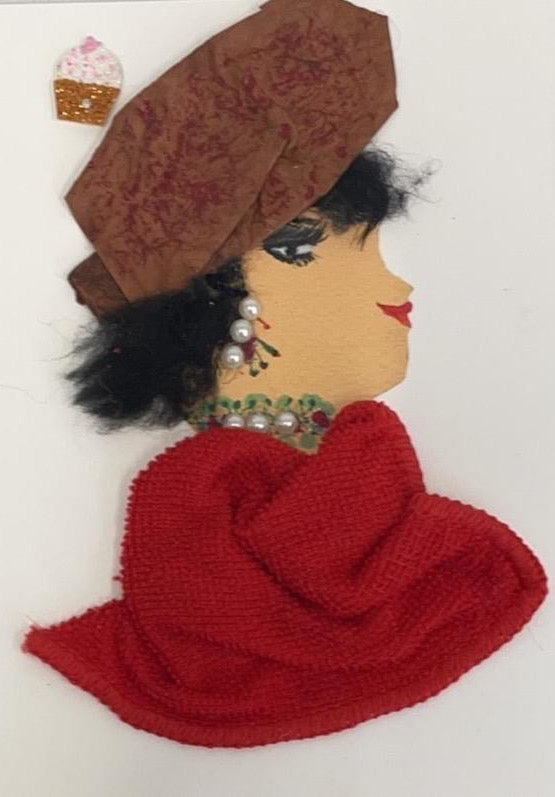 This card has been called Red Ruislip Ruby. She wears a red towel material blouse and a brown hat. In the top left corner, she has a cupcake sticker. 