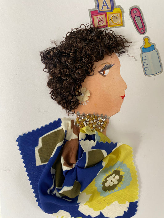 I designed this card of a woman named Magnificent Mary. She has a white skin tone and is wearing a beautiful blue floral blouse. She wears a silver and yellow necklace and floral earrings. In the corner there is a bottle, a paper clip, and letter blocks.