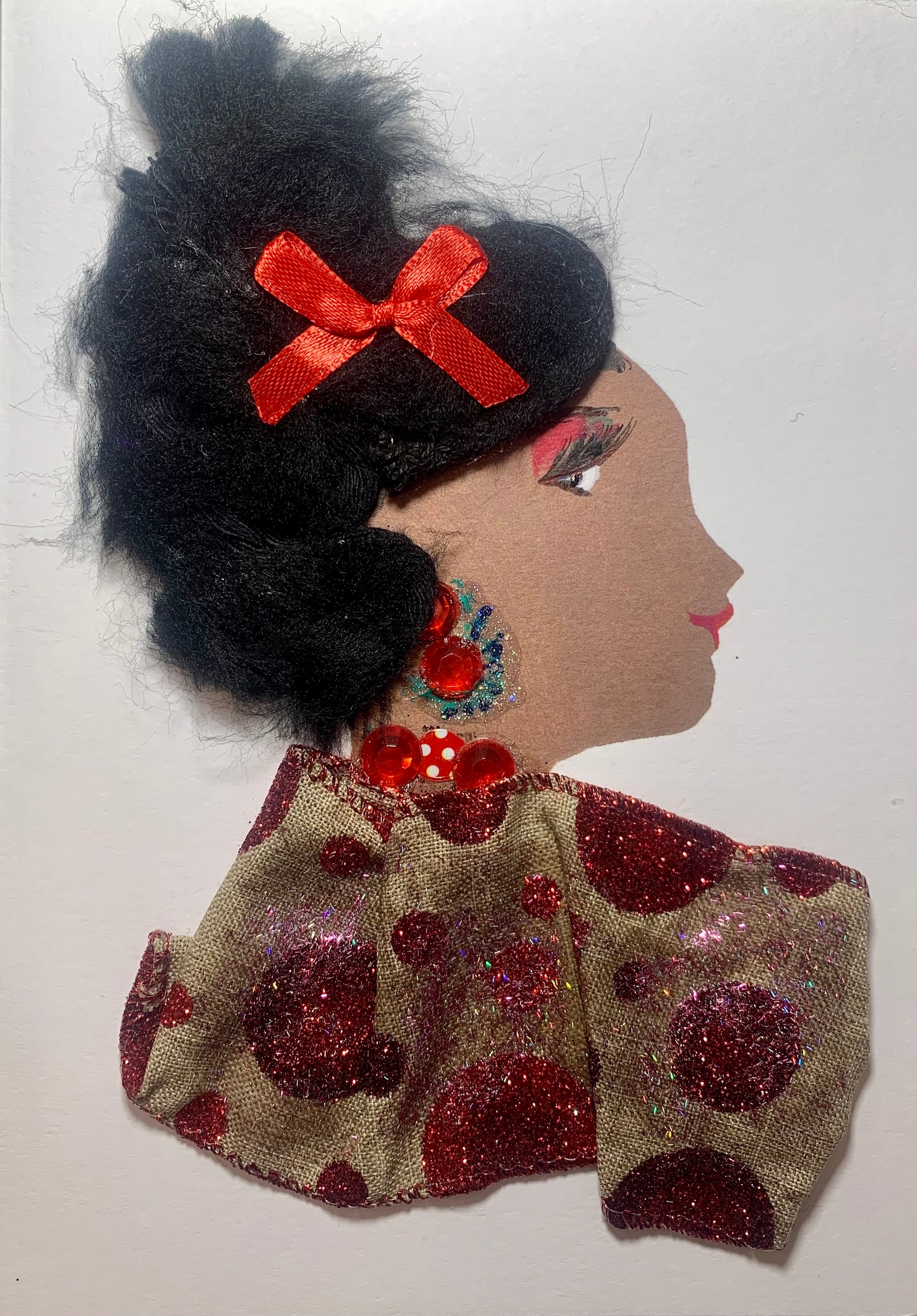 This card is of a woman named Vero Paris. She wears a blouse with red glitter polka dots on it. Her jewellery is made of red gems, and there is a red bow in her black hair. 